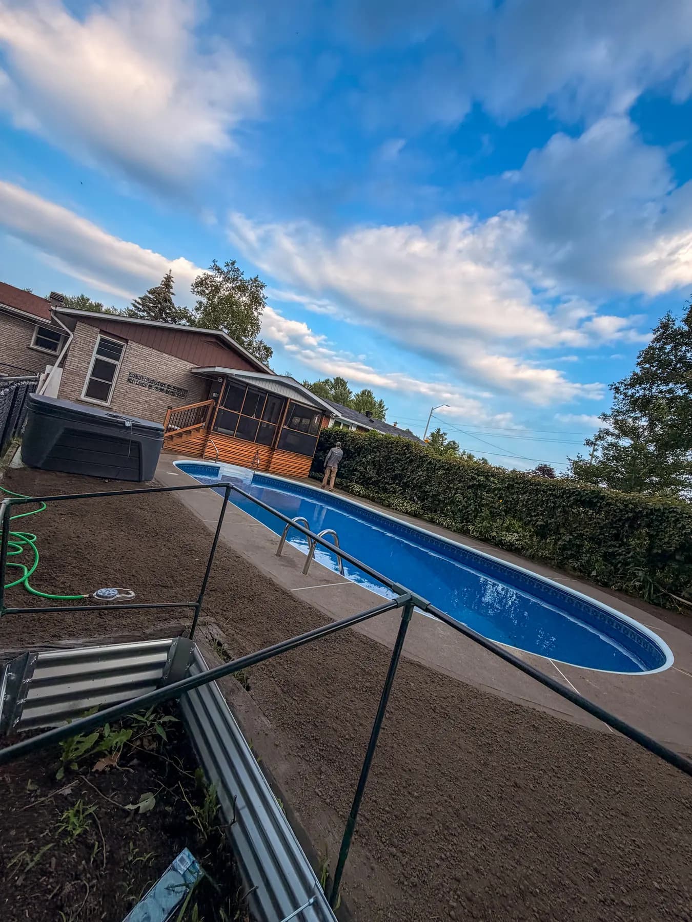 Evening view of the finished backyard with fresh grading around the pool and hot tub