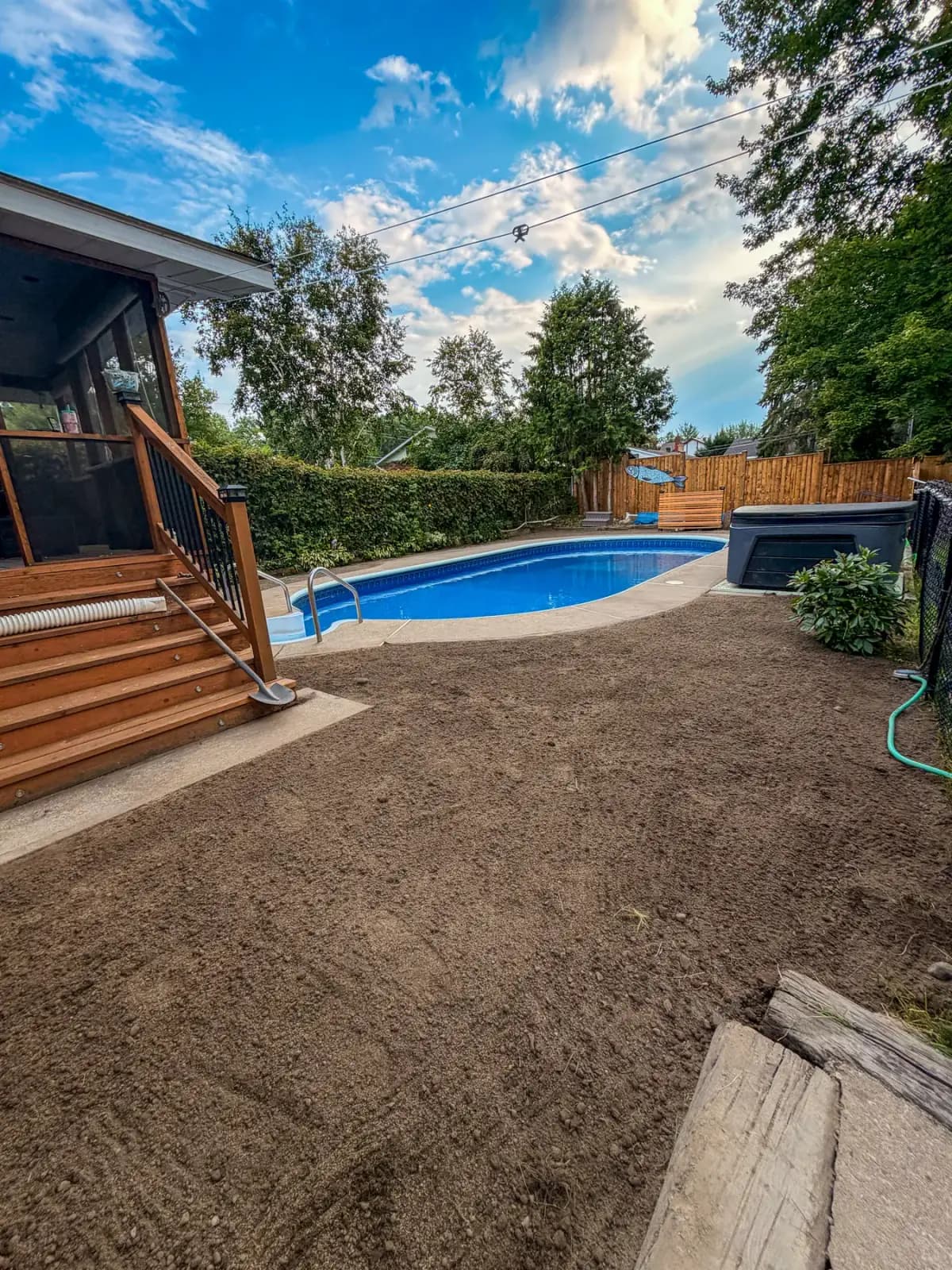 Fresh topsoil graded smooth around the backyard pool after the old patio tear-out