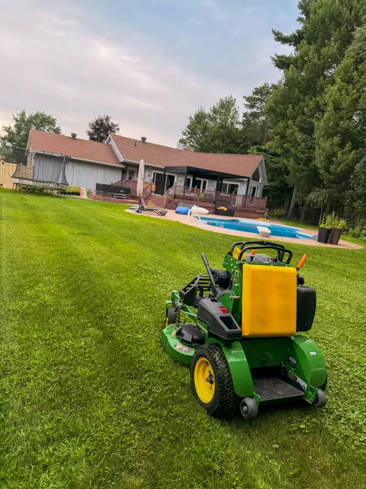 Freshly mowed poolside lawn with a stand-on mower at a large Ottawa Valley property