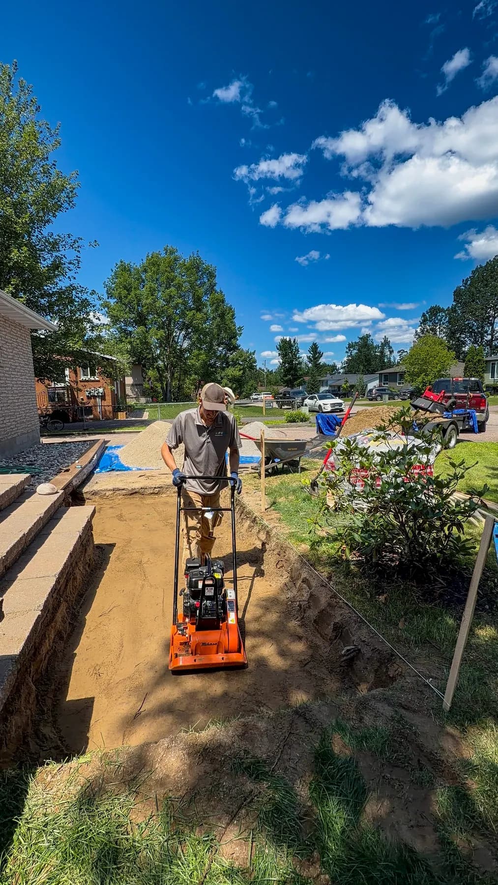 Crew member compacting the gravel base with string lines set.