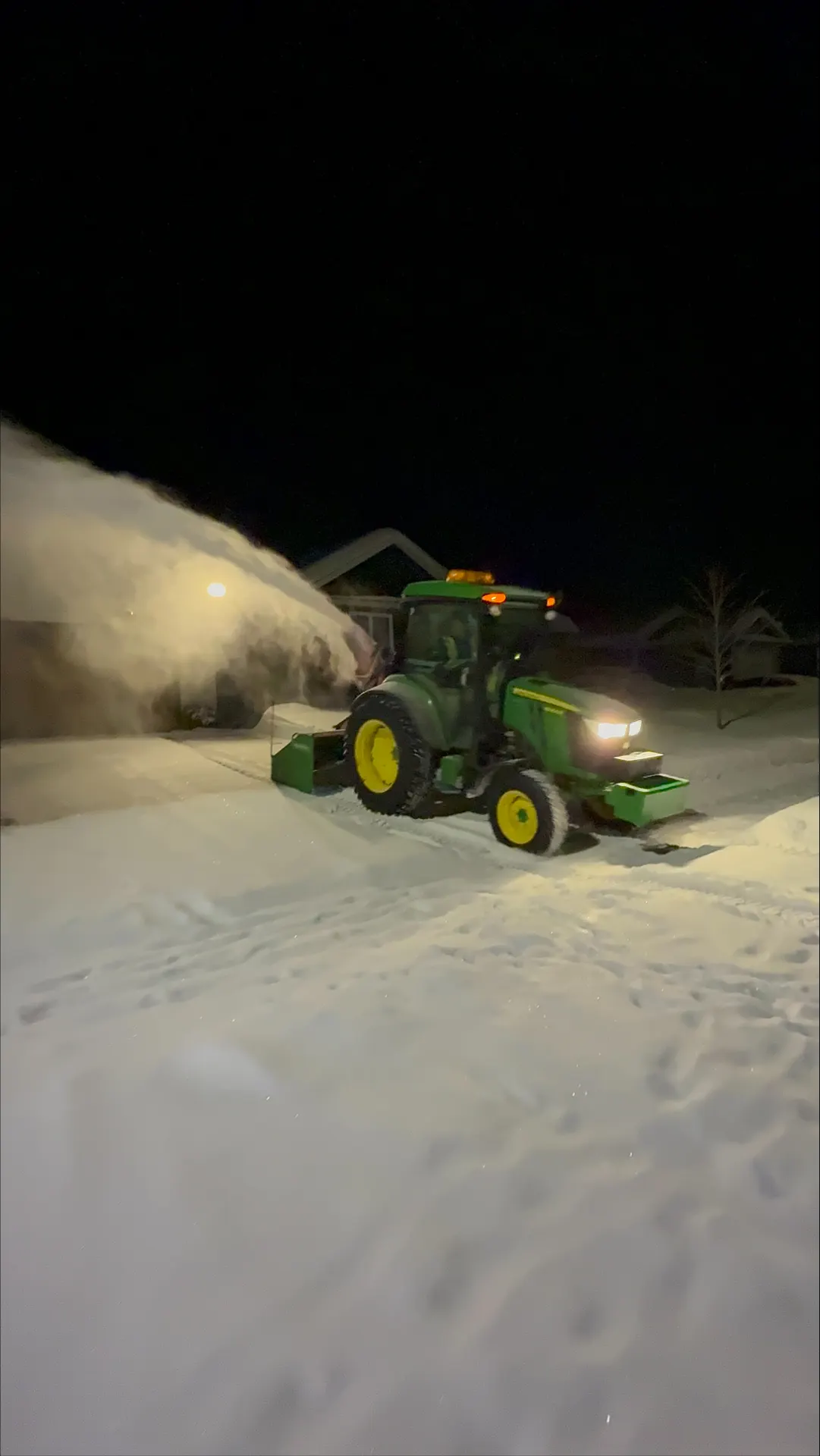 PVS tractor throwing a plume of snow at night