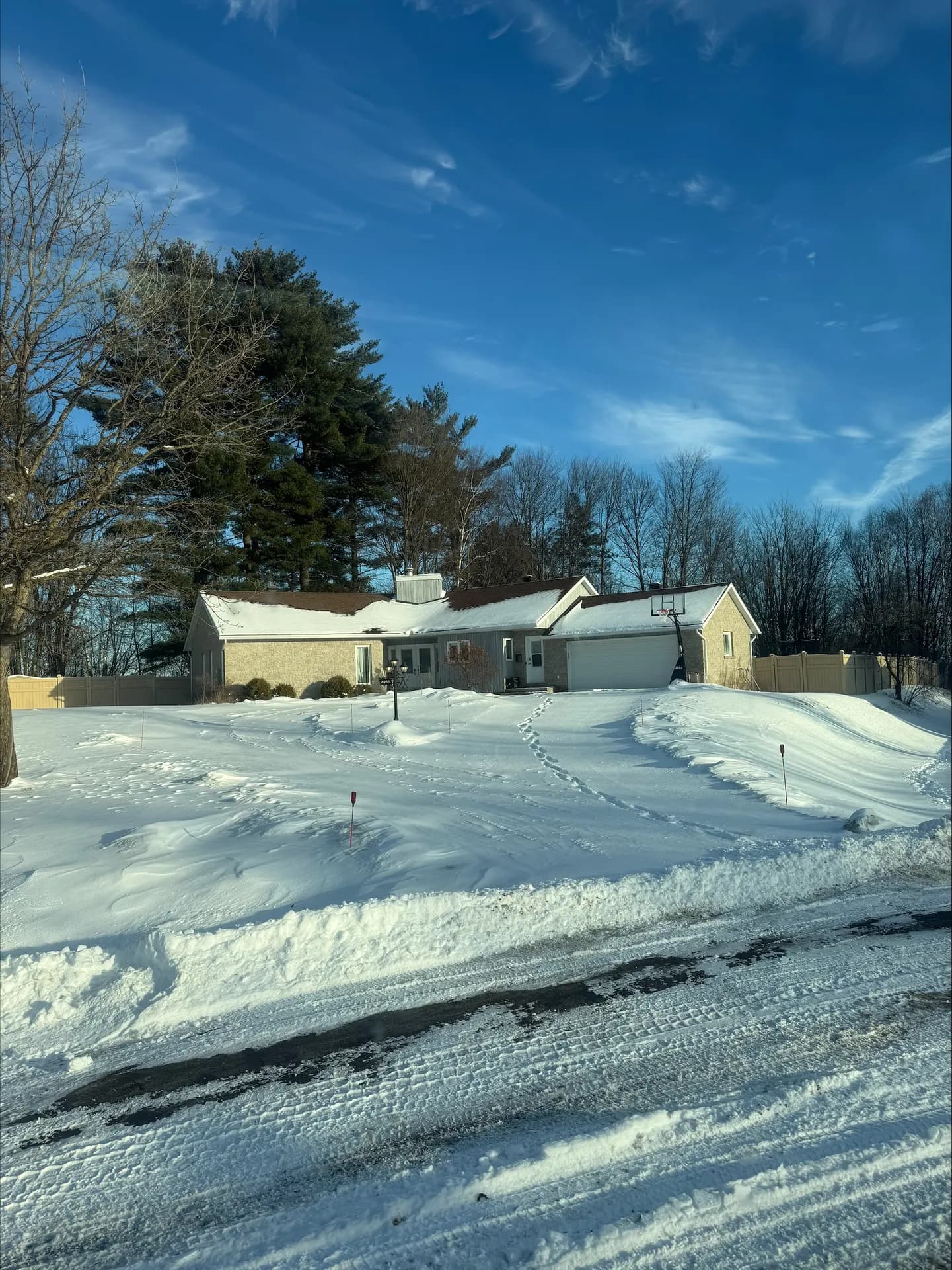 Snow-covered Ottawa Valley home with a cleared driveway under a blue sky